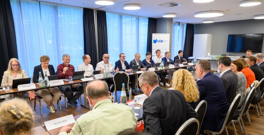 Öffnet eine Lightbox: Blick in den Veranstaltungsraum auf verschiedene Teilnehmer 