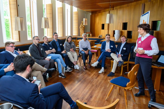 Öffnet eine Lightbox: Verschiedene Personen sitzen im Kreis und hören jemandem zu 